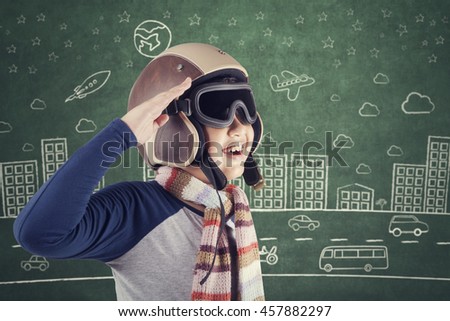 Photo of a little boy wearing an aviator helmet and smiling happy with picture on the chalkboard