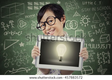 Picture of a female elementary school student showing lightbulb with a digital tablet screen in the class
