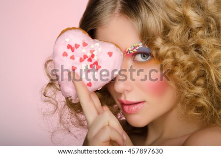 European woman with donut in face on pink background