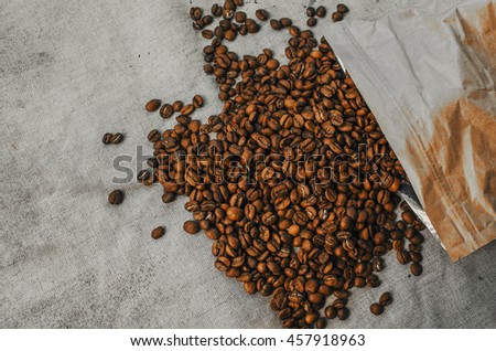 Roasted brown coffee beans and paper coffee package,  background and texture