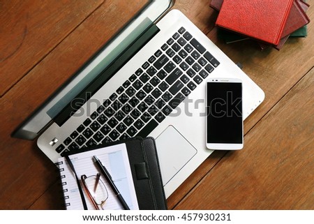Workplace with notebook, wooden table and laptop laying,copy space .comfortable working space, internet laptop headphone smart phone notepad paper pen eyeglasses mouse laying on it