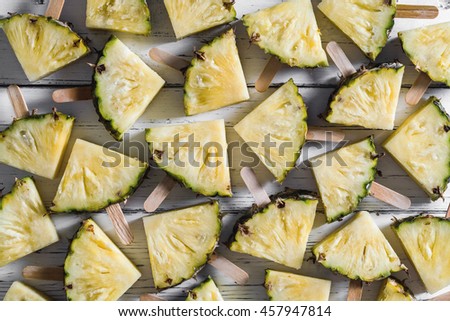 Pineapple slice popsicles on a white rustic wood background
