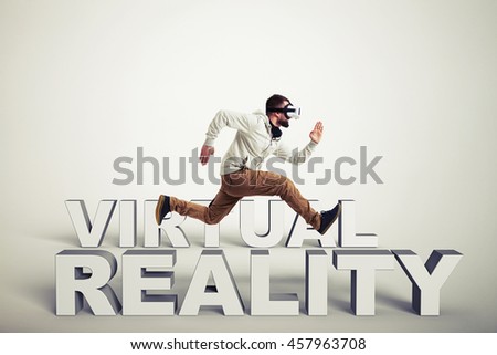 Young bearded man in virtual reality glasses running between 3d words isolated over white background