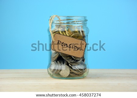 Coins in a jar on wooden table with PENSION tag. Navy blue background.