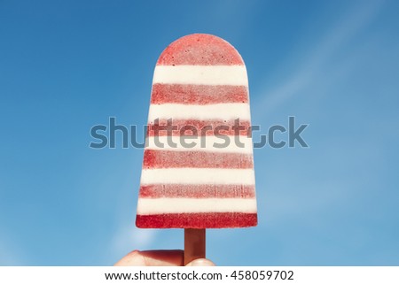 Ice cream held up to the hot blue sky