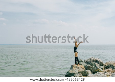 young woman is engaged in meditation, stretching, yoga on the beach background