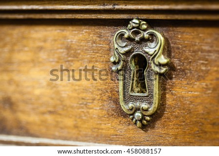an antique and weathered keyhole on a desk drawer Royalty-Free Stock Photo #458088157