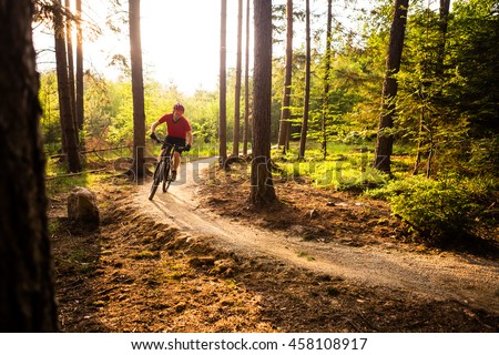 Mountain biker riding on bike in spring inspirational mountains landscape. Man cycling MTB on enduro trail track. Sport fitness motivation and inspiration outdoors in sunset woods. Royalty-Free Stock Photo #458108917