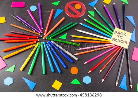 Back to school background with a lot of colorful felt-tip pens and colorful pencils in circles and  title "Back to school" written on the yellow pieces of paper on the black school chalkboard