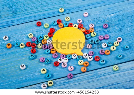 Social Media Chat Concept. Yellow blank empty chat bubble for text on blue wooden background. Symbol of live chat. Office table desk with set of colorful supplies. Top view and copy space for ad text