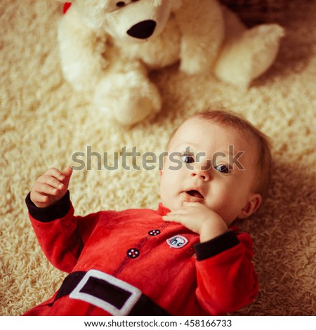 little newborn girl dressed as Santa on the floor