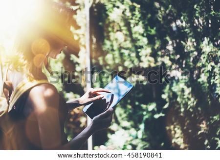 Hipster young girl with bright backpack and vintage camera using tablet or holding gadget. View tourist traveler with sunglasses on background Parc Laberint Barcelona. Mock up for text message
