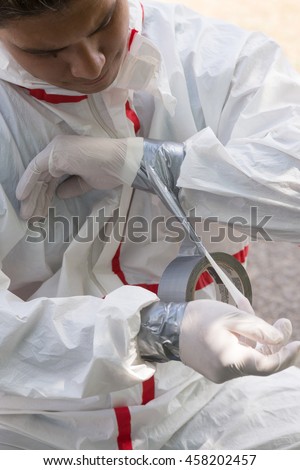A house painter secures the sleeves of his hazmat suit preparing to safely remove lead paint.