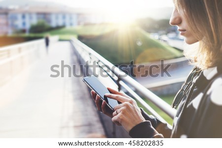 Hipster texting message on smartphone or technology, mock up of blank screen. Tourist girl using cellphone on bridge background. Female hands holding gadget on blur. Mockup copy space for text message