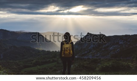 Hipster young girl with bright backpack enjoying sunset on peak of foggy mountain. Tourist traveler on background valley landscape view mockup. Hiker looking sunlight in trip in northern Spain 