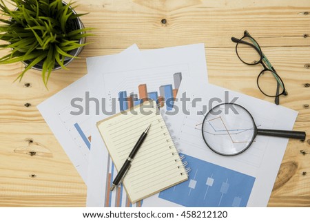 Office workplace with Magnifying glass on wood table,supplies and reports for analysis business plan