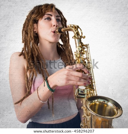 Girl with dreadlocks playing the saxophone over textured background