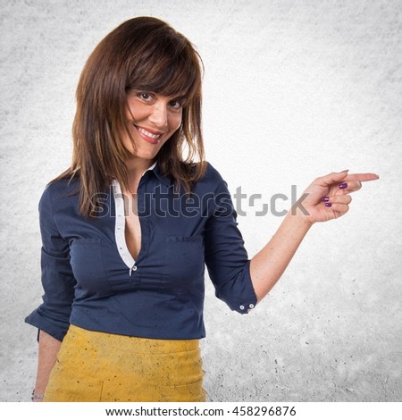 Pretty woman pointing to the lateral over textured background
