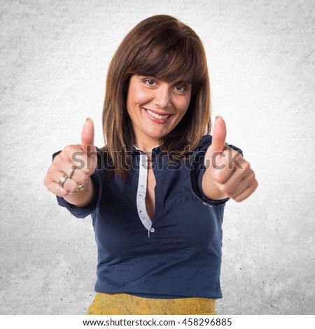 Pretty woman with thumb up over textured background
