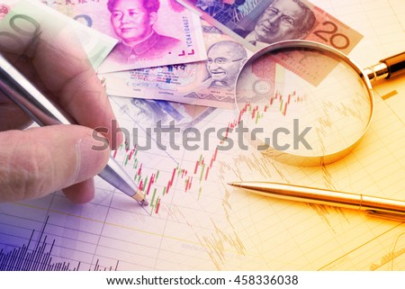 Hand holding a blue ballpoint pen is analysing a technical chart of financial instrument. A concept of forex / currency trading trend analysis for investor who want to maximize portfolio profits. Royalty-Free Stock Photo #458336038