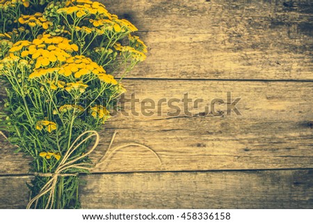Yellow flowers from summer meadow, rustic bouquet located on wooden background