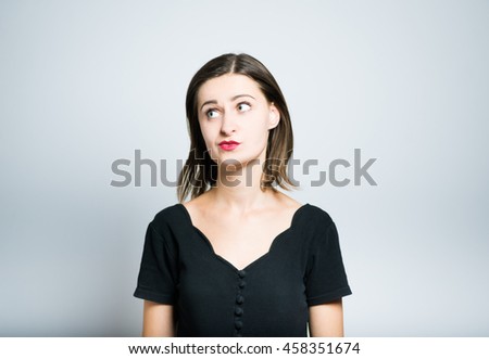 Pretty slim girl doubts studio photo isolated on a gray background