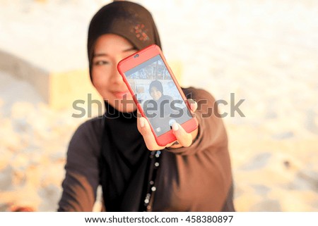 Young asian muslim woman taking selfie on the beach
