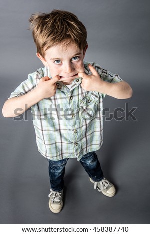 standing red hair young boy enjoying making a funny face with his big mouth for mischievous misbehavior, high angle view, grey background