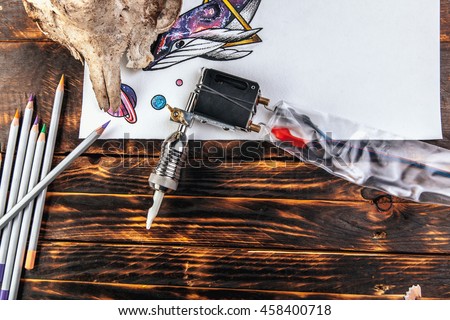 beautiful sketch drawing sea whale and planets with colored pencils lying on old wooden background, tattoo machine and skull of a goat