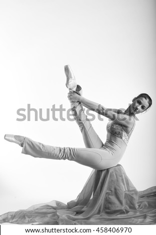 sports girl in a ballet hall in complex poze.balerina warming up, light tones picture. daylight falls on the blonde