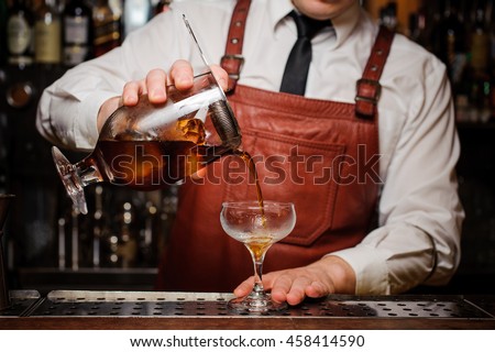 Bartender pouring fresh cocktail in fancy glass Royalty-Free Stock Photo #458414590