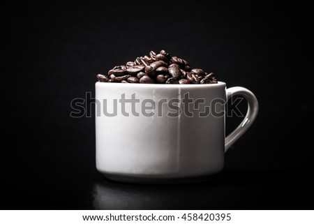Coffee beans in the cup on black background. Toned.