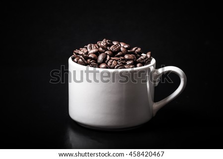 Coffee beans in the cup on black background. Toned.