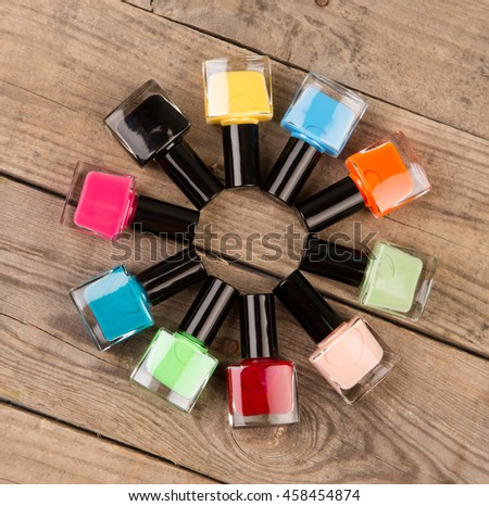 Colored nail polish bottles stacked circle on brown wooden table