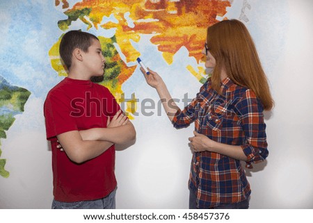 Redheaded girl student with a guy considered a world map