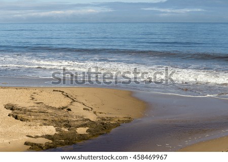 Tranquil scenic view of  the  Indian Ocean waves breaking onto the  rocks on the sandy shore  at  Ocean Beach Bunbury Western Australia on a fine  morning in winter  is fascinating to watch