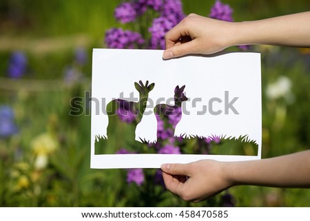 holding paper cut miniature tree over blooming flowers