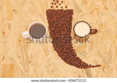Roasted coffee beans on a wooden background in a pot of coffee and milk