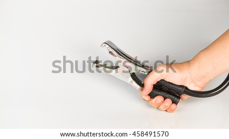 Hand holding negative black color jumper or battery booster cable for cars, trucks and SUV on plain background. Concept or recharging. Slightly de-focused and close-up shot. Copy space