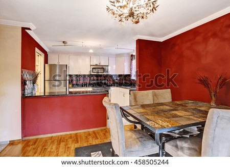 Dining area connected to kitchen with red walls, hardwood floor and vintage chandelier. Northwest, USA