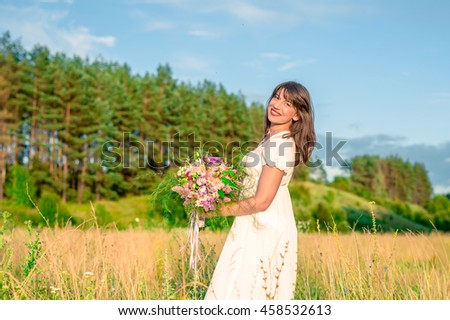 young brunette woman with a bouquet in hand spinning and dancing in the forest and fields
