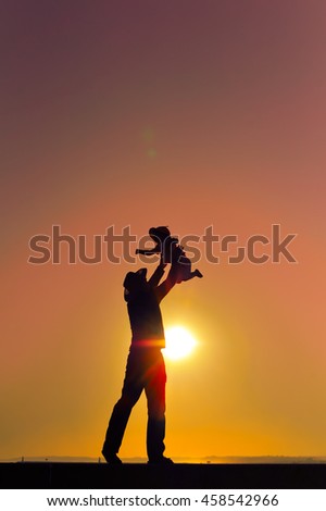 Joyful silhouette of father throwing up his child at sunset outdoors background. Book cover concept design