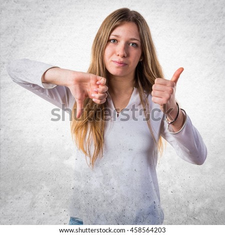 Teen girl making good-bad sign over textured background