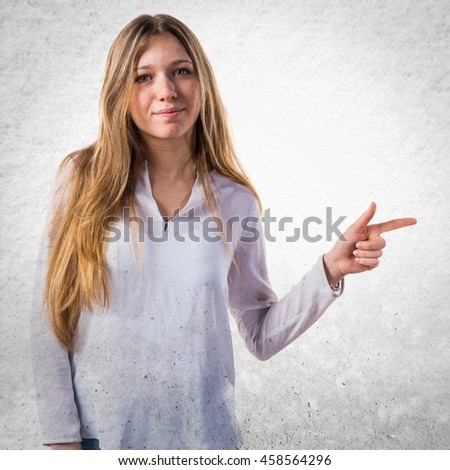 Teen girl pointing to the lateral over textured background