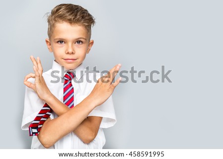 Studio portrait of male elementary pupil on light grey