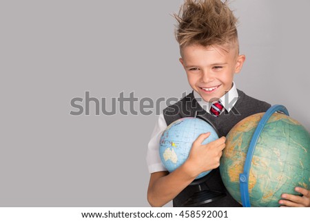 Cheerful smiling little boy on a grey background. Looking at camera. Back to school concept