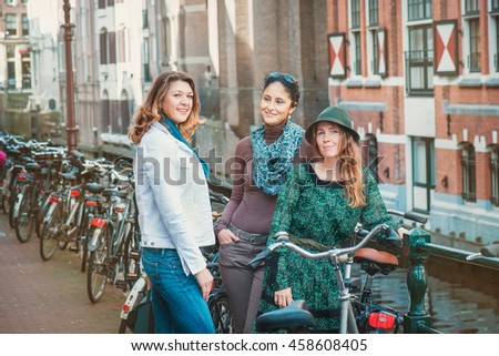 Tourists with bicycles taking a tour along the narrow canals and old houses of Amsterdam