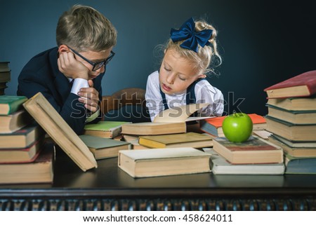 School kids reading a book at library. Motivate your child to study boring subject. Table with many books and one green apple. Children dressed in school uniform and glasses. Student. Grade retention