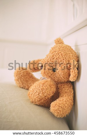 Lonely Teddy Bear sitting in the white room. Concept about waiting for someone and loneliness. (Focus on bear's eye - Vintage Style)