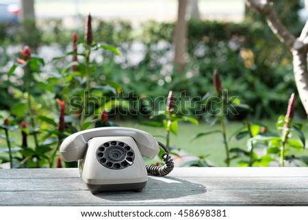 A vintage or old Retro rotary telephone on wood table with outdoor park.